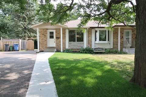 a small brick house with a sidewalk in front of it