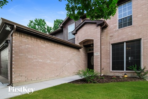 a side view of a brick house with a sidewalk and grass