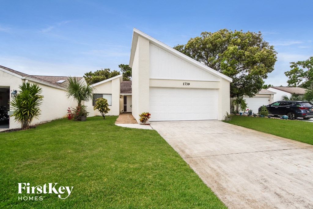 a white house with a driveway and a lawn