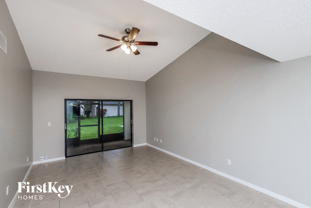 the spacious living room with ceiling fan and tile flooring