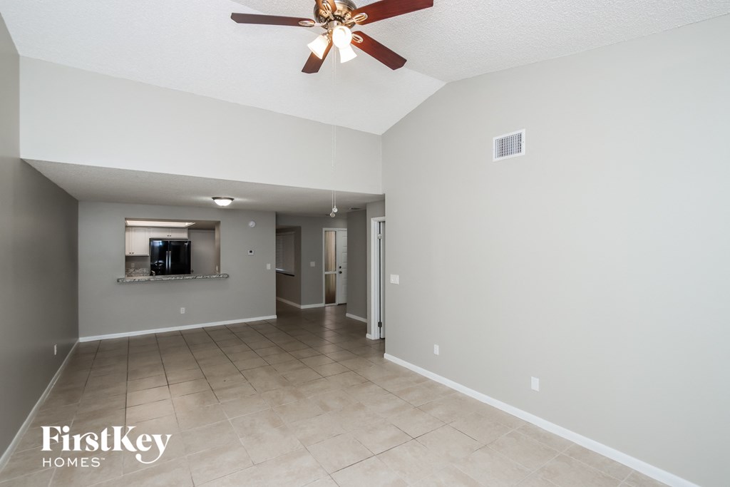 a spacious living room with a ceiling fan and tile flooring