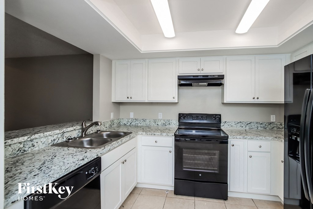 a kitchen with white cabinets and black appliances and granite counter tops