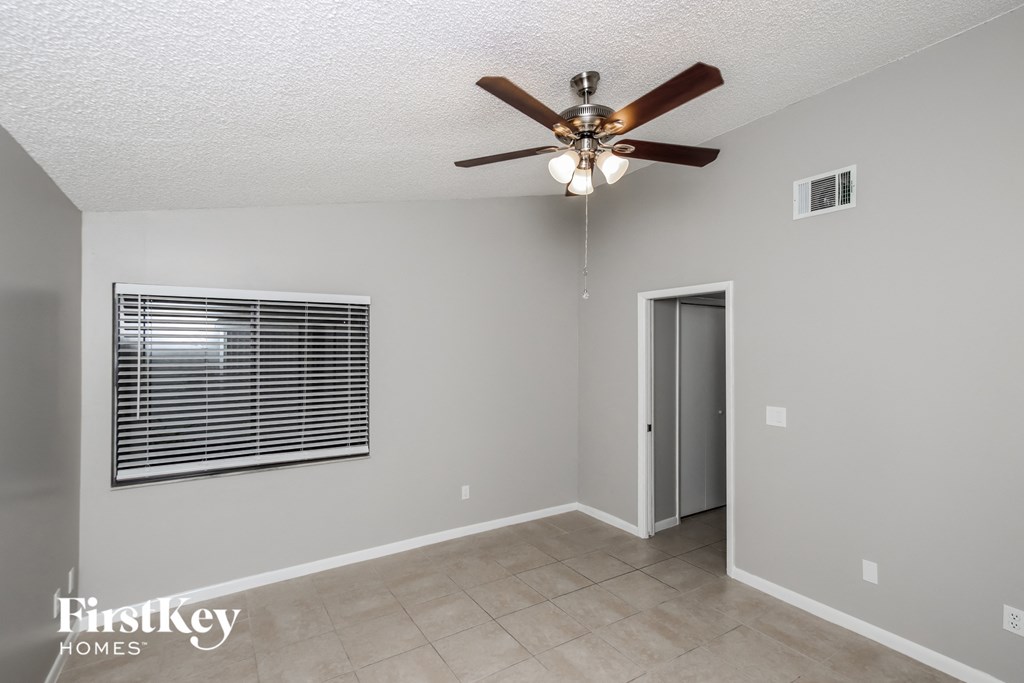the living room has a ceiling fan and a door to the hallway