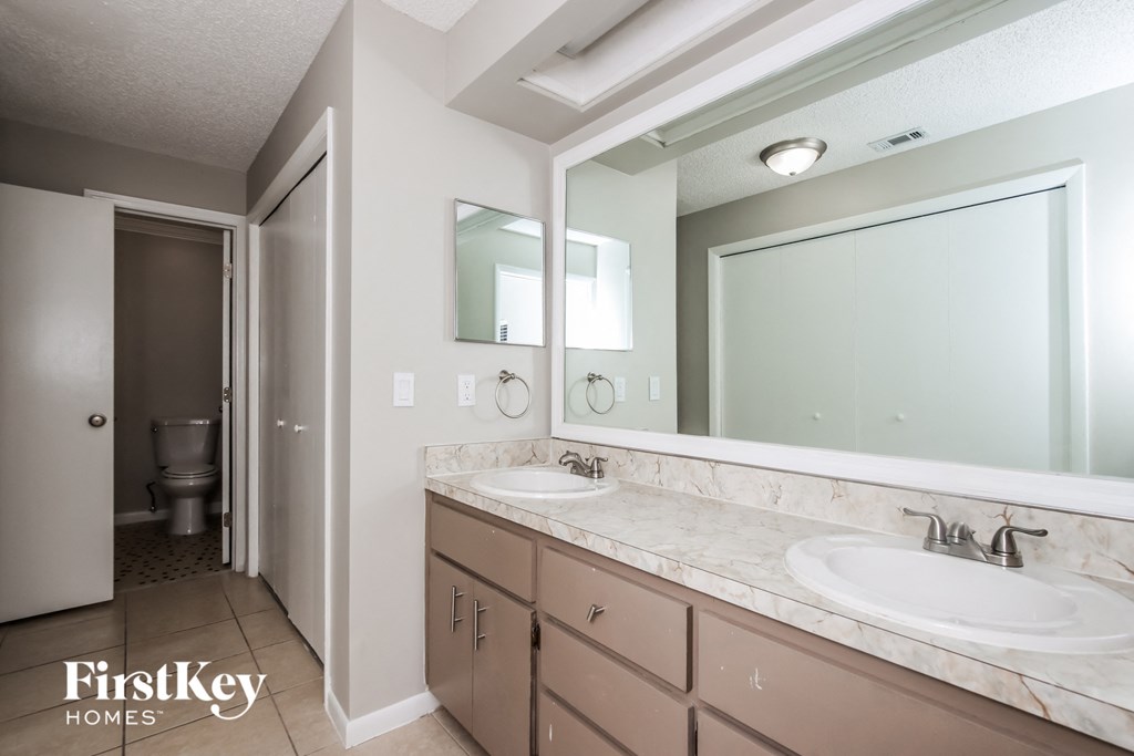 the master bathroom has dual sinks and a large mirror
