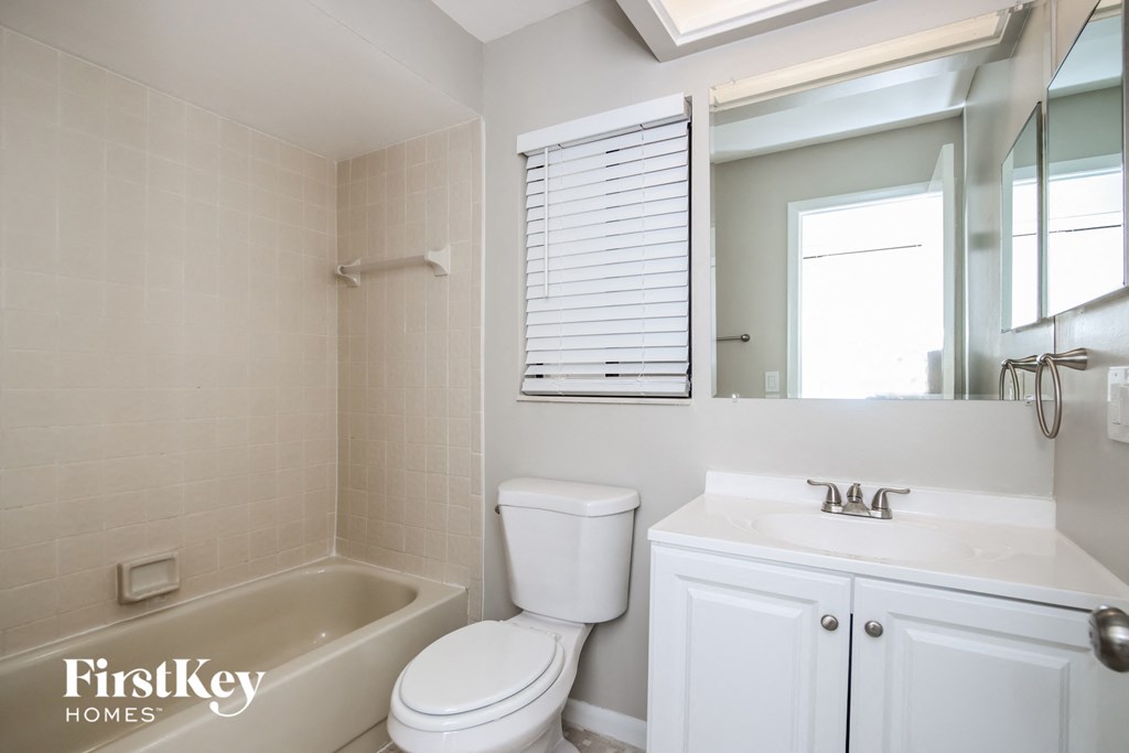 a bathroom with a toilet sink and tub and a mirror