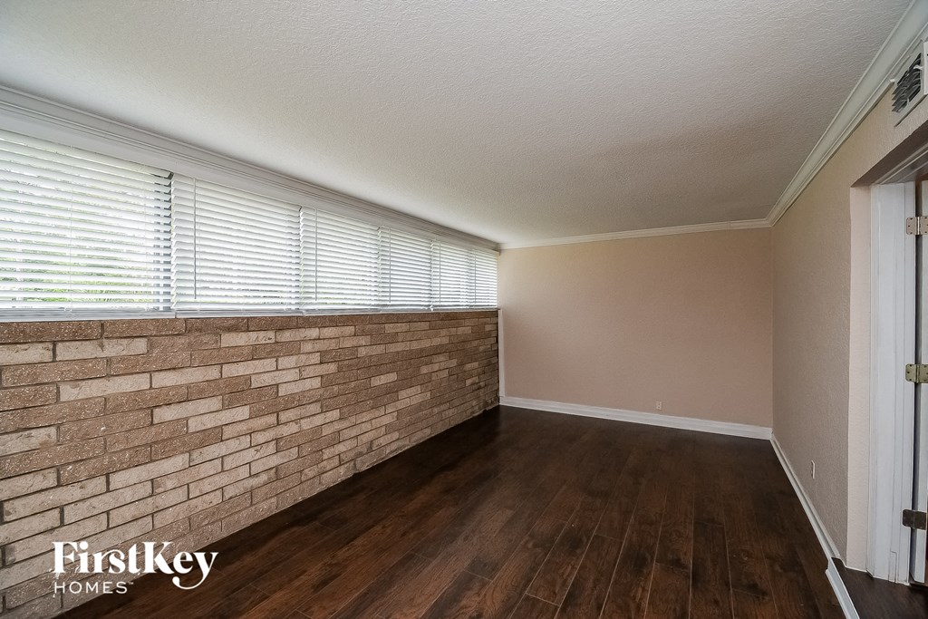 an empty living room with a brick wall and wood floors