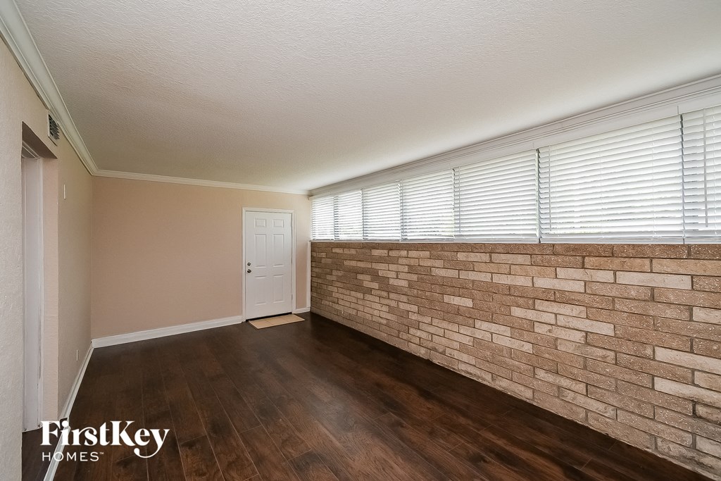 a living room with a brick wall and wood floors