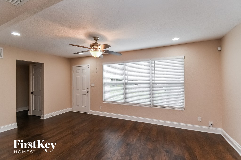 an empty living room with a ceiling fan and a large window