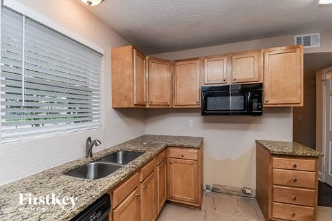 a kitchen with wooden cabinets and granite counter tops and a sink