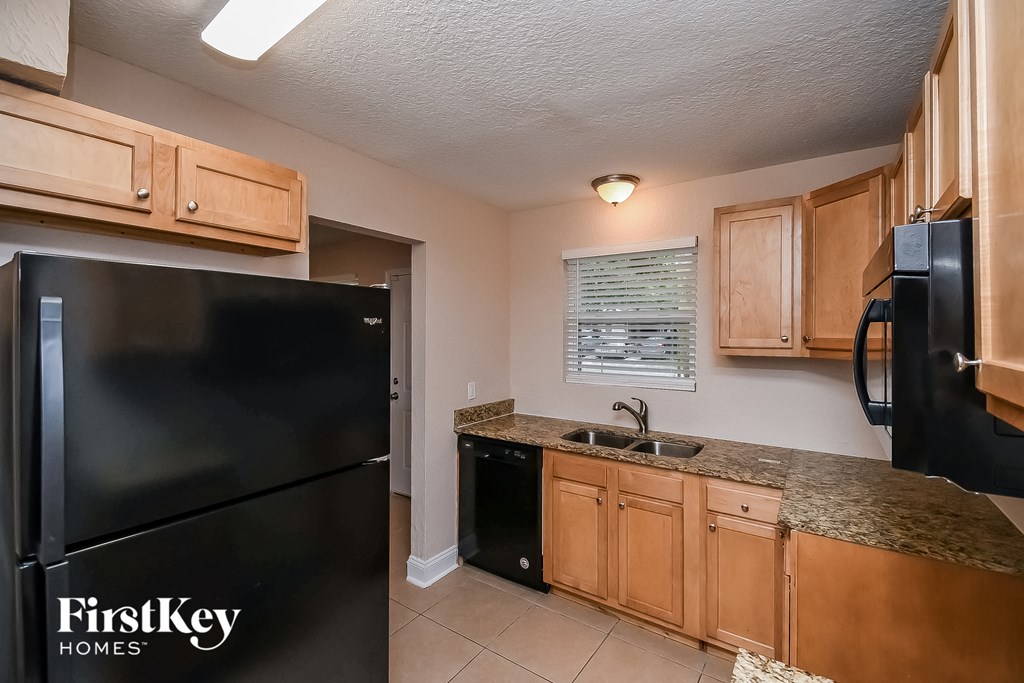 a kitchen with wooden cabinets and a black refrigerator
