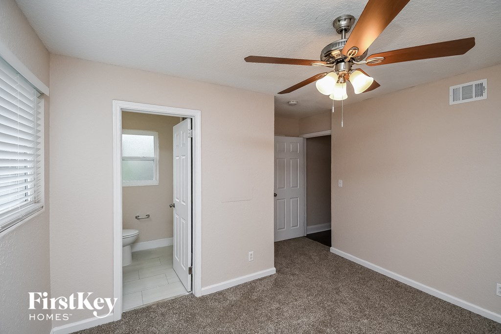 a bedroom with a ceiling fan and a door to a bathroom