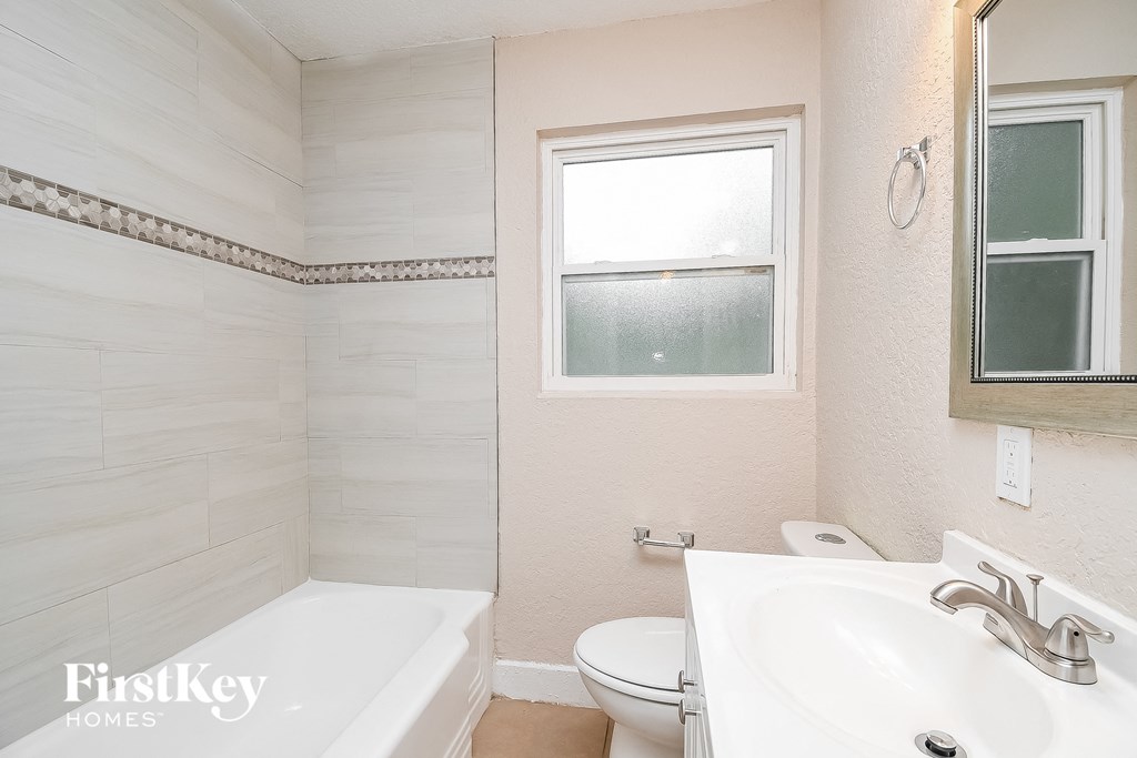 a bathroom with a sink toilet and tub and a window
