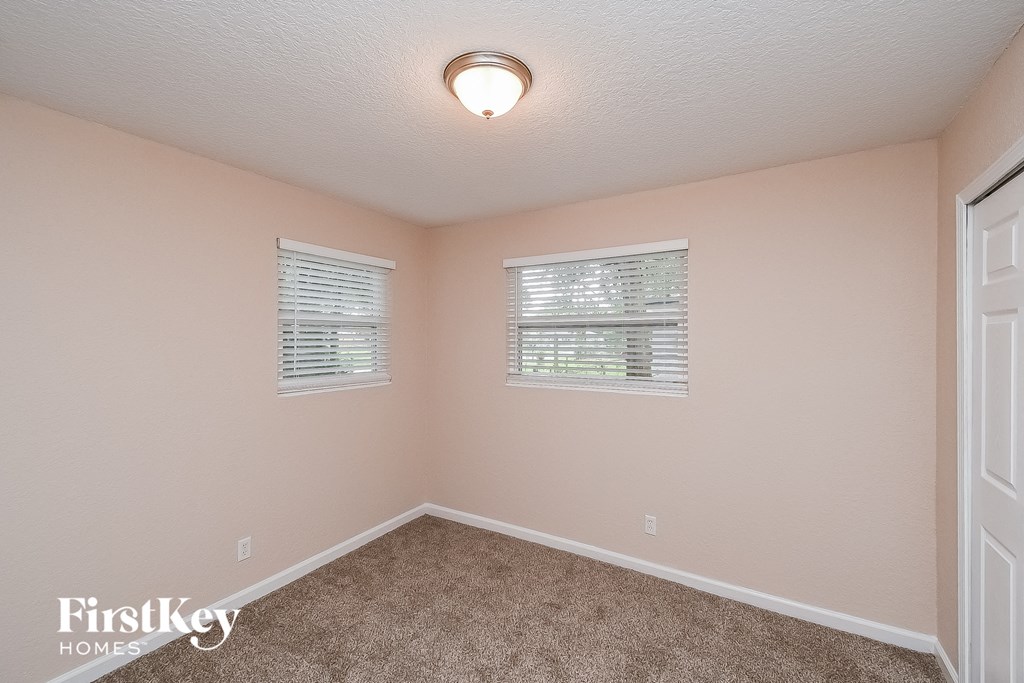 a bedroom with a carpeted floor and two windows