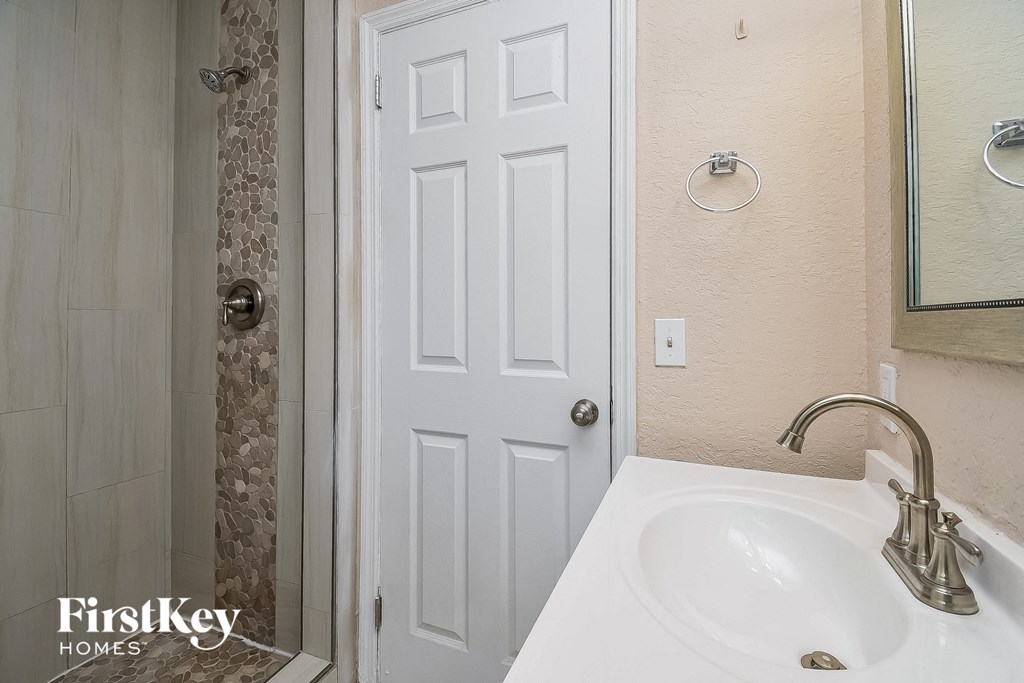 a bathroom with a sink and a shower and a white door