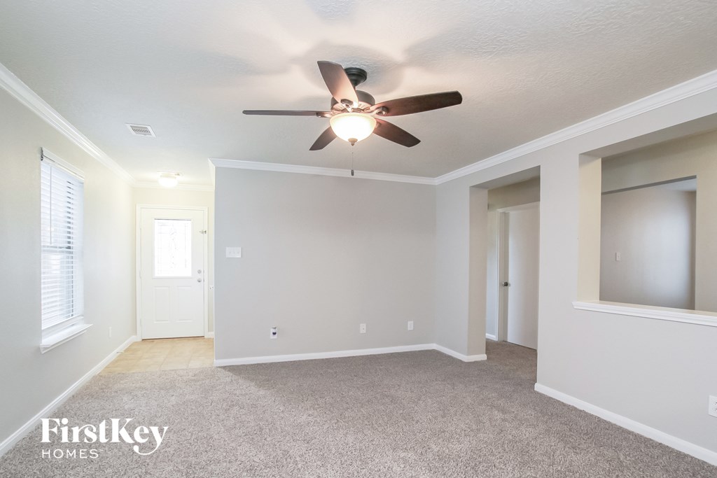 the living room of an empty home with a ceiling fan
