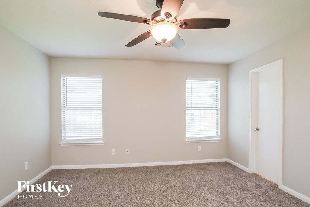 a bedroom with a ceiling fan and two windows