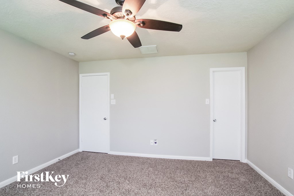 a bedroom with a ceiling fan and two doors