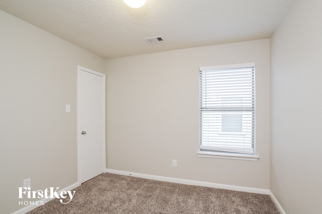a bedroom with carpet and a window and a door