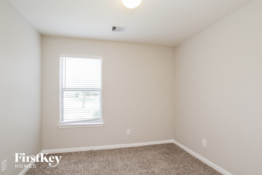 a bedroom with white walls and a window and carpet