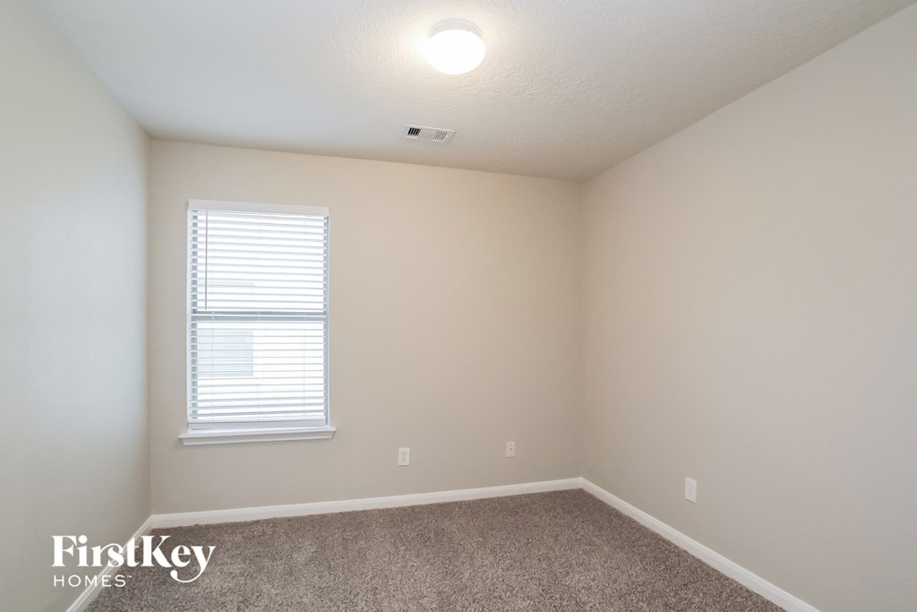 a bedroom with white walls and a window and a carpet