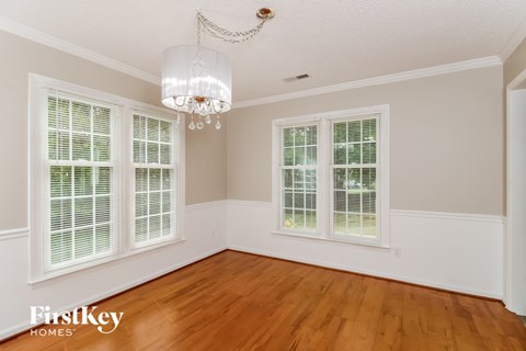 an empty dining room with windows and a chandelier