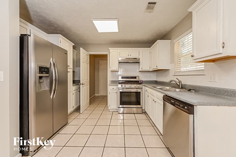 A kitchen with white cabinets and a stainless steel refrigerator.