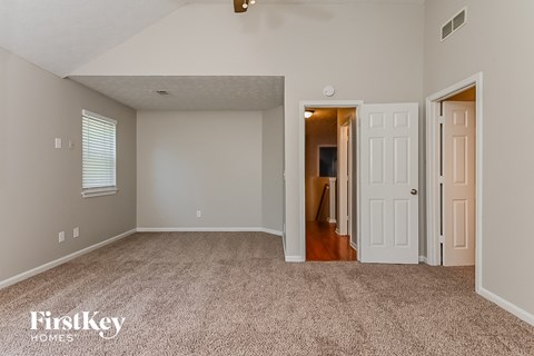 A spacious room with a carpeted floor and a ceiling fan.