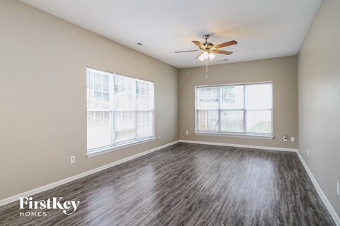 A room with a ceiling fan and wood flooring.