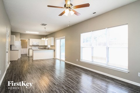 A spacious living room with a ceiling fan and hardwood floors.