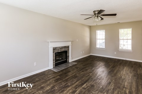 A spacious room with a fireplace and a ceiling fan.