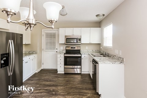 A kitchen with a refrigerator, oven, and sink.