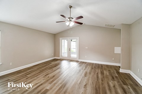 an empty living room with hardwood flooring and a ceiling fan