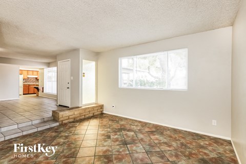 A room with a tile floor and a window showing trees outside.