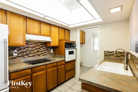 A kitchen with wooden cabinets and a stone backsplash.