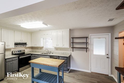 a kitchen with white cabinets and black appliances and a blue table