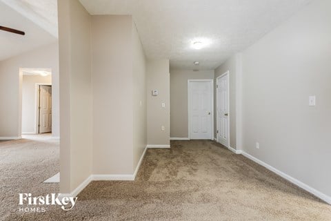 a spacious living room with carpet and a door to a bedroom