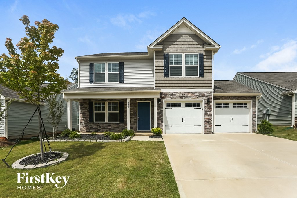 A two-story house with a garage and a tree in front.