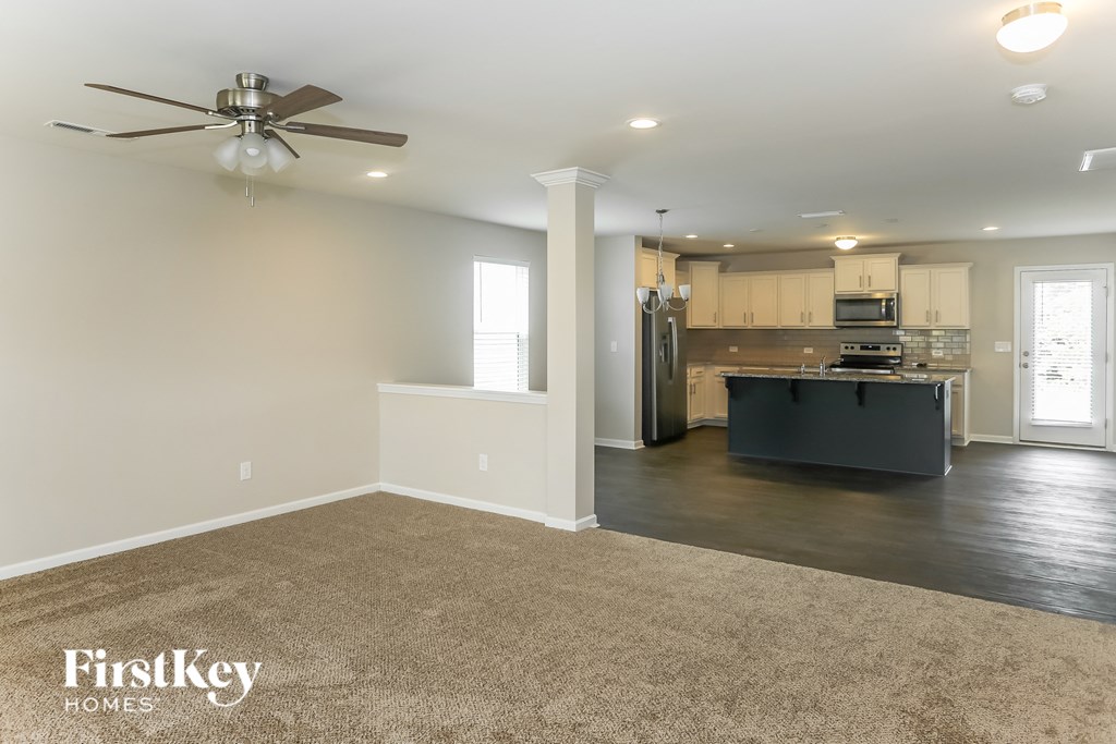 A spacious living room with a kitchen in the background.