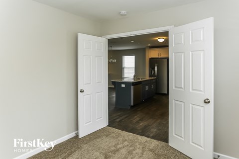 A white door opens to a kitchen with a counter and cabinets.