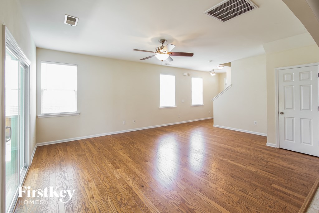 A spacious room with wooden floors and a ceiling fan.