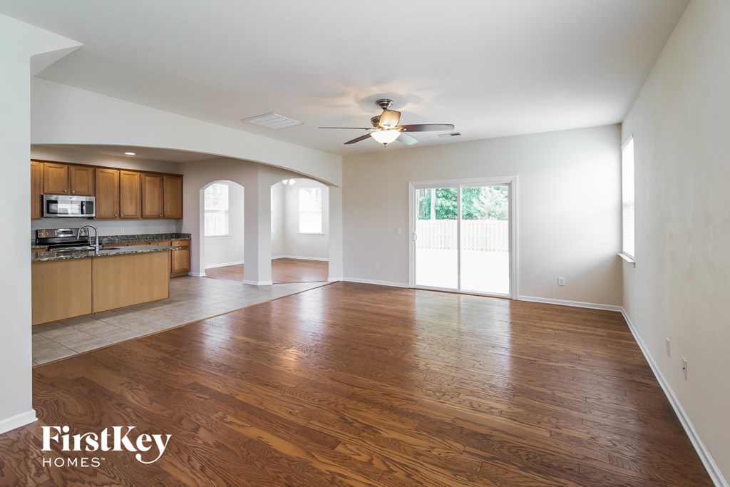 A spacious room with wooden floors and a ceiling fan.