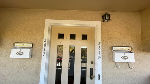 the front door of an apartment building with mailboxes on the side