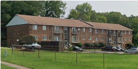 A large brick apartment building with a parking lot in front.