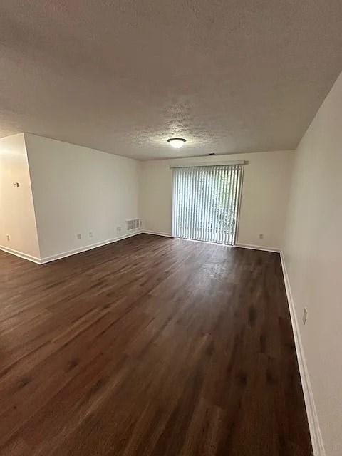 A room with wooden flooring and a window with blinds.