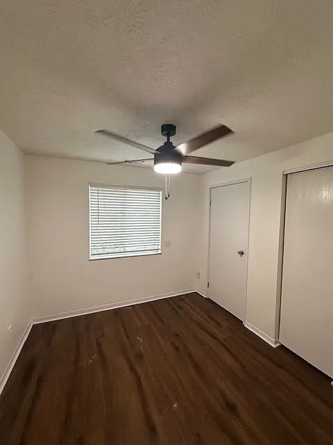 A room with a ceiling fan and a window with blinds.