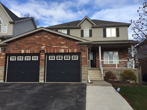 A house with a brick facade and two black garage doors.