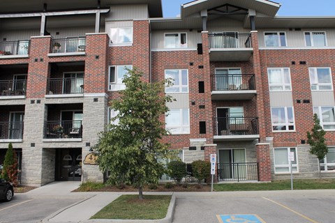 a red brick apartment building with balconies and a tree in the yard