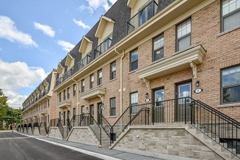 A row of red brick townhouses with black railings and white trim.