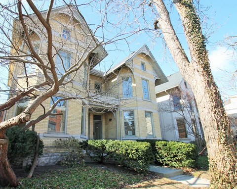 A large, two-story house with a yellowish exterior and a green roof.