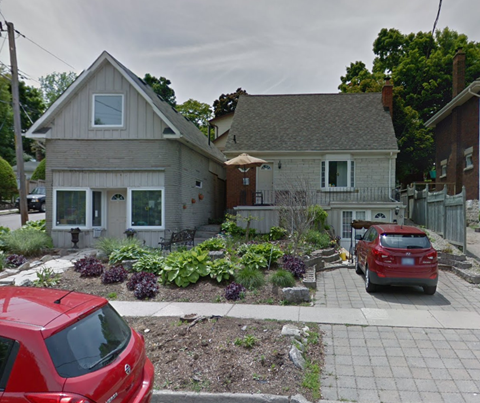 A red car is parked in front of a house.